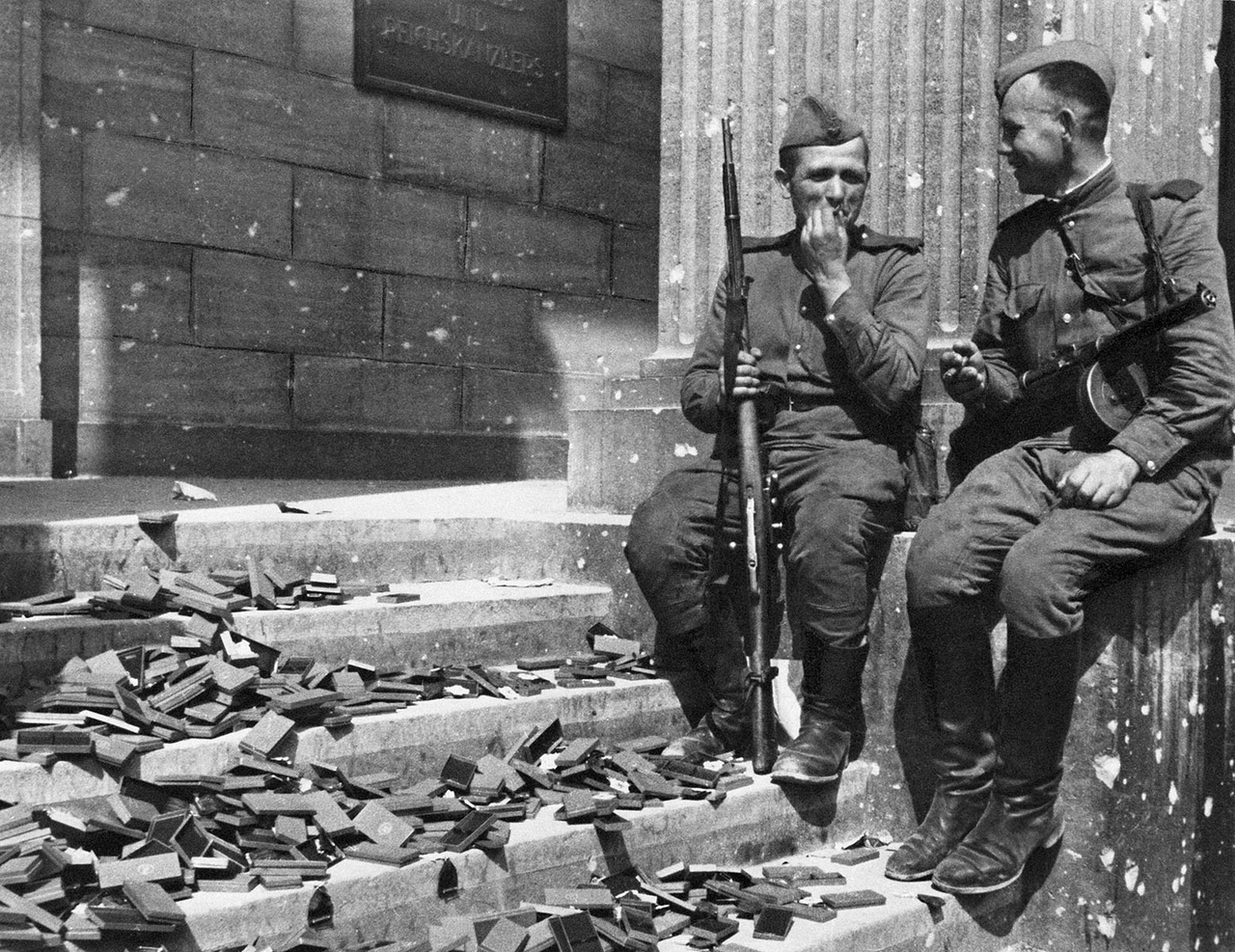 «Перекур у рейхсканцелярии». Советские воины у входа в Имперскую канцелярию. Все ступени завалены крестами, которые хранились в фашистском логове. Берлин, 1945 год.